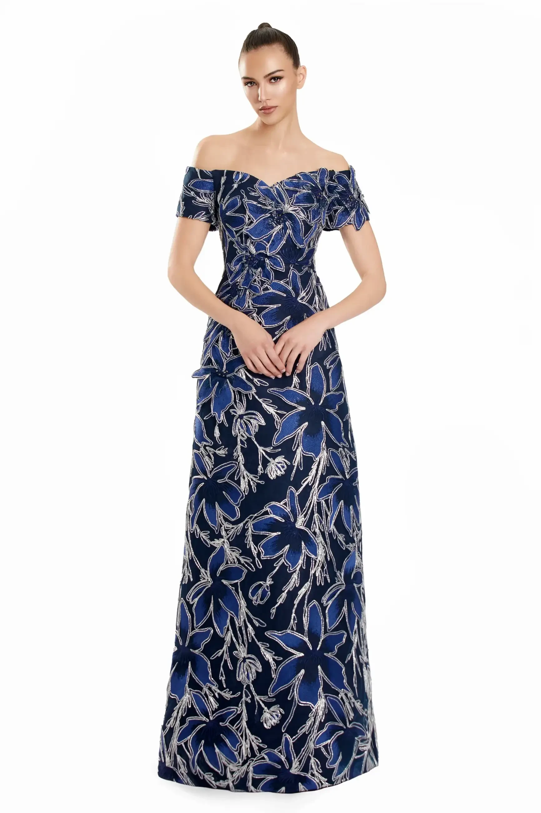 Model is wearing a regal navy and silver off-the-shoulder A-line gown with bold floral embroidery.