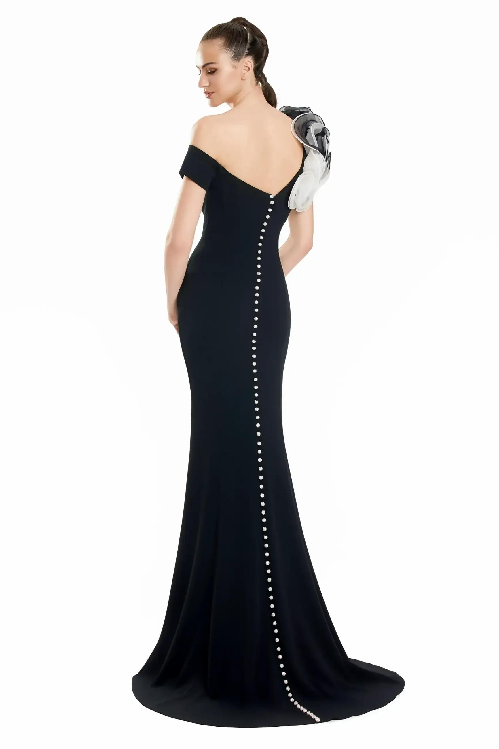 Model is wearing a chic black fit-and-flare gown with a dramatic textured accent sleeve and a trail of buttons down the back.
