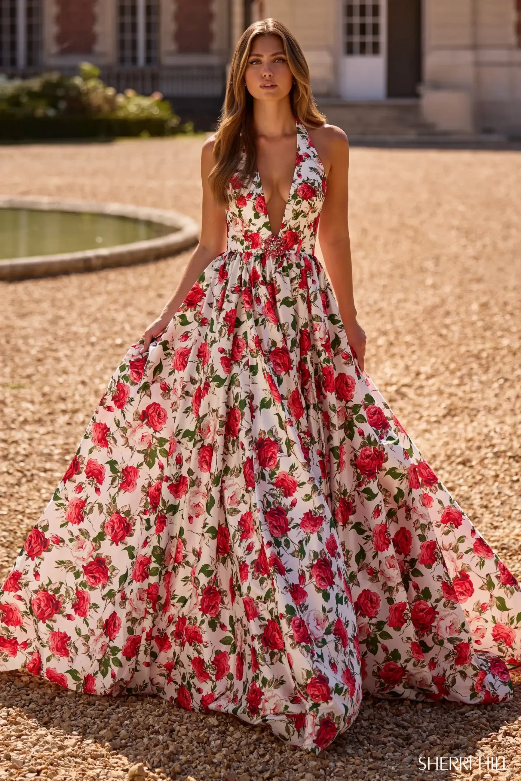 model is wearing a sleeveless red floral prom dress